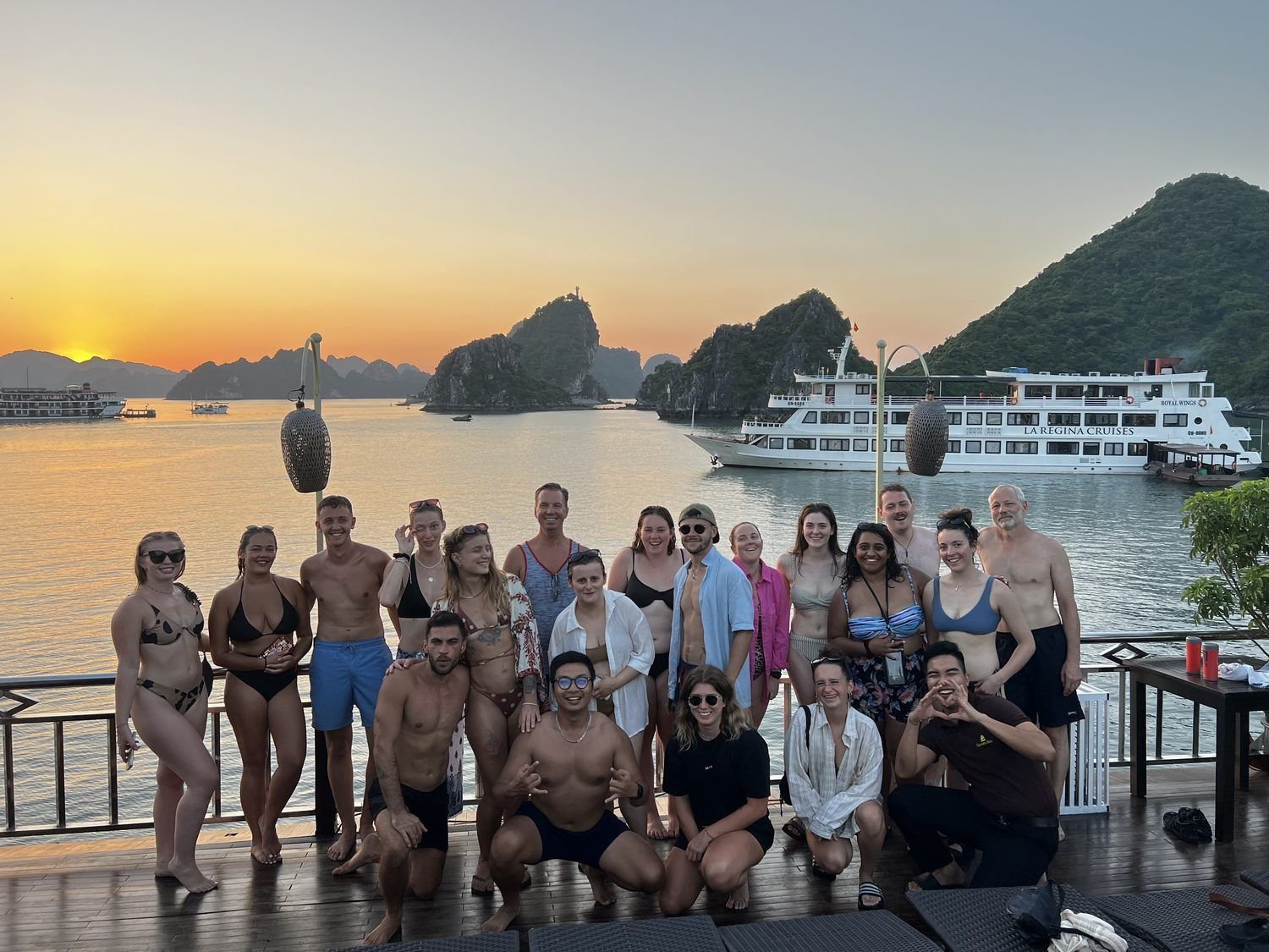 A tour group on a cruise deck at sunset in Ha Long Bay