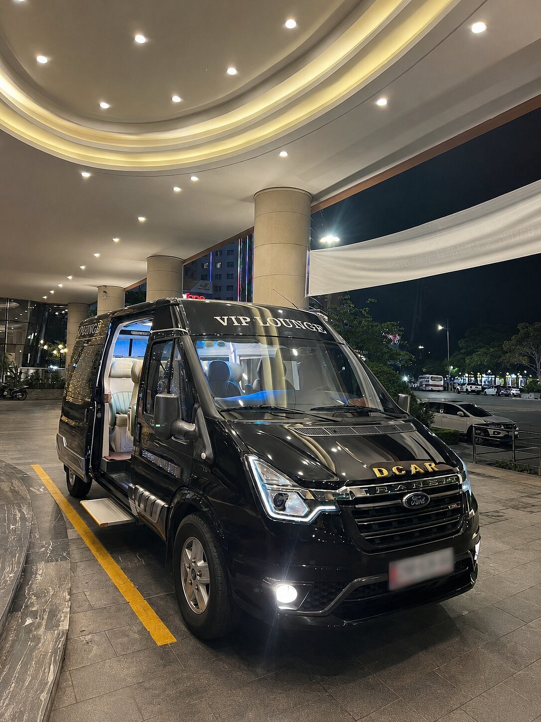 A black VIP limousine van waiting at a hotel entrance at night