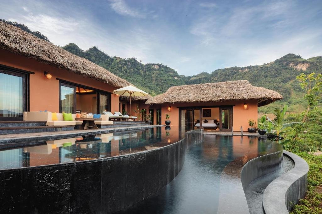 Thatched private villas around an infinity pool in the mountains of northern Vietnam