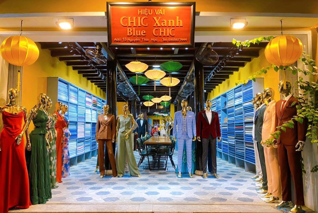 A tailor shop on a quiet Hoi An old town street in the morning, with suits on mannequins