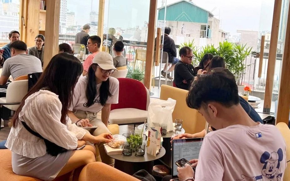 Busy café in Vietnam with people working on laptops by large open windows